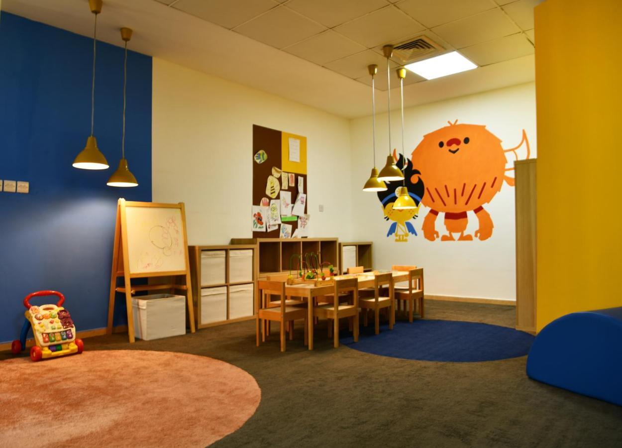 Al Raha Beach Resort & Spa Abu Dhabi Exterior photo The photo shows a colorful children's classroom or play area. The walls are painted in various shades, including blue and yellow. There is a large, playful character mural on one wall that appears to be a friendly monster. 

In the room, there is a s