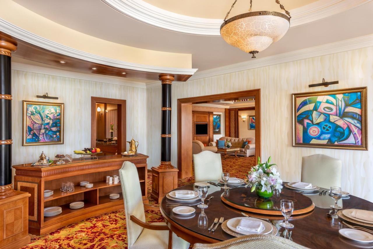 Al Raha Beach Resort & Spa Abu Dhabi Exterior photo The photo shows an elegantly designed dining area and a glimpse into a luxurious living space. 

In the foreground, a round dining table is set with fine china, glassware, and a centerpiece featuring fresh flowers. The chairs surrounding the table ha