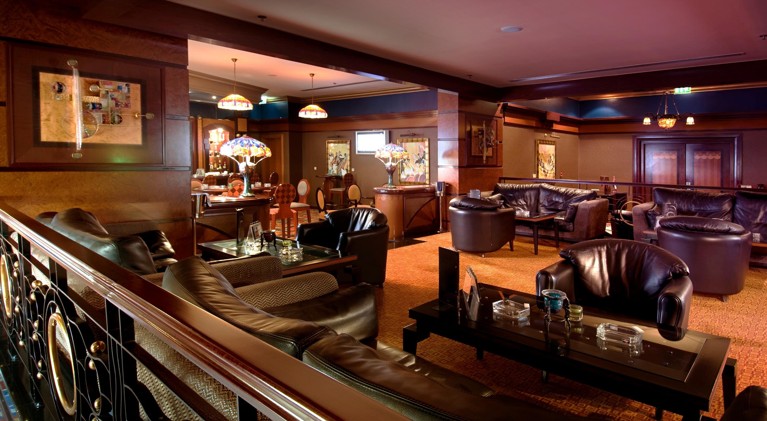 Al Raha Beach Resort & Spa Abu Dhabi Interior photo The photo depicts a stylish lounge area featuring comfortable seating and an inviting atmosphere. There are several plush leather armchairs and sofas arranged around low tables. The space is well-lit, with stained glass lamps providing warm light. Th