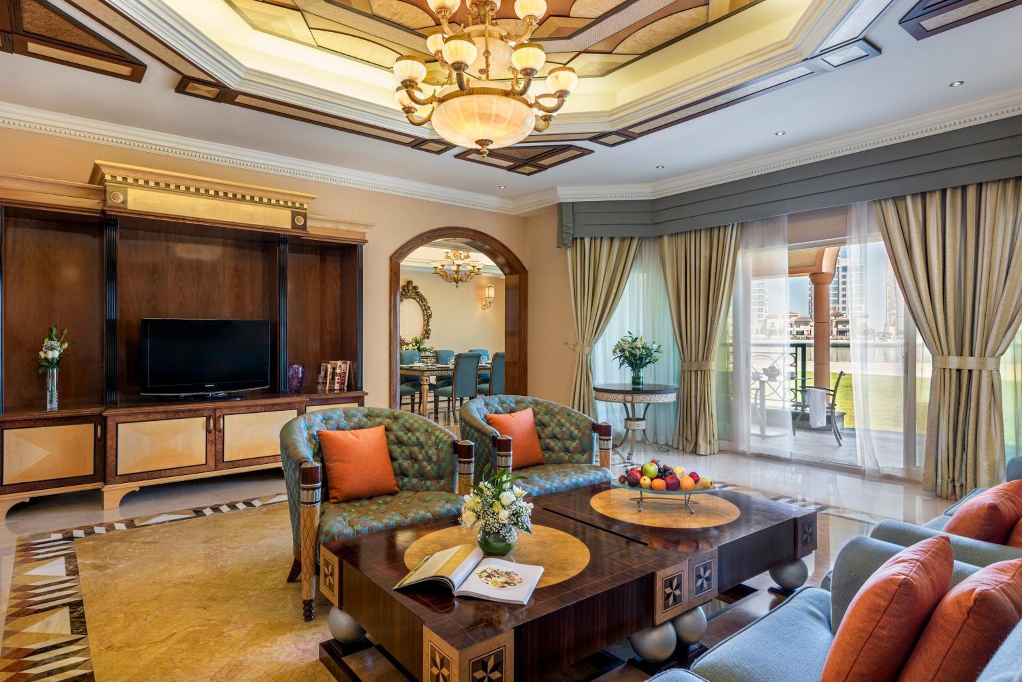 Al Raha Beach Resort & Spa Abu Dhabi Exterior photo The photo depicts a luxurious living room with elegant decor. It features two green upholstered sofas accented with orange pillows, arranged around a stylish coffee table. The coffee table showcases decorative items, including a magazine and a bowl o