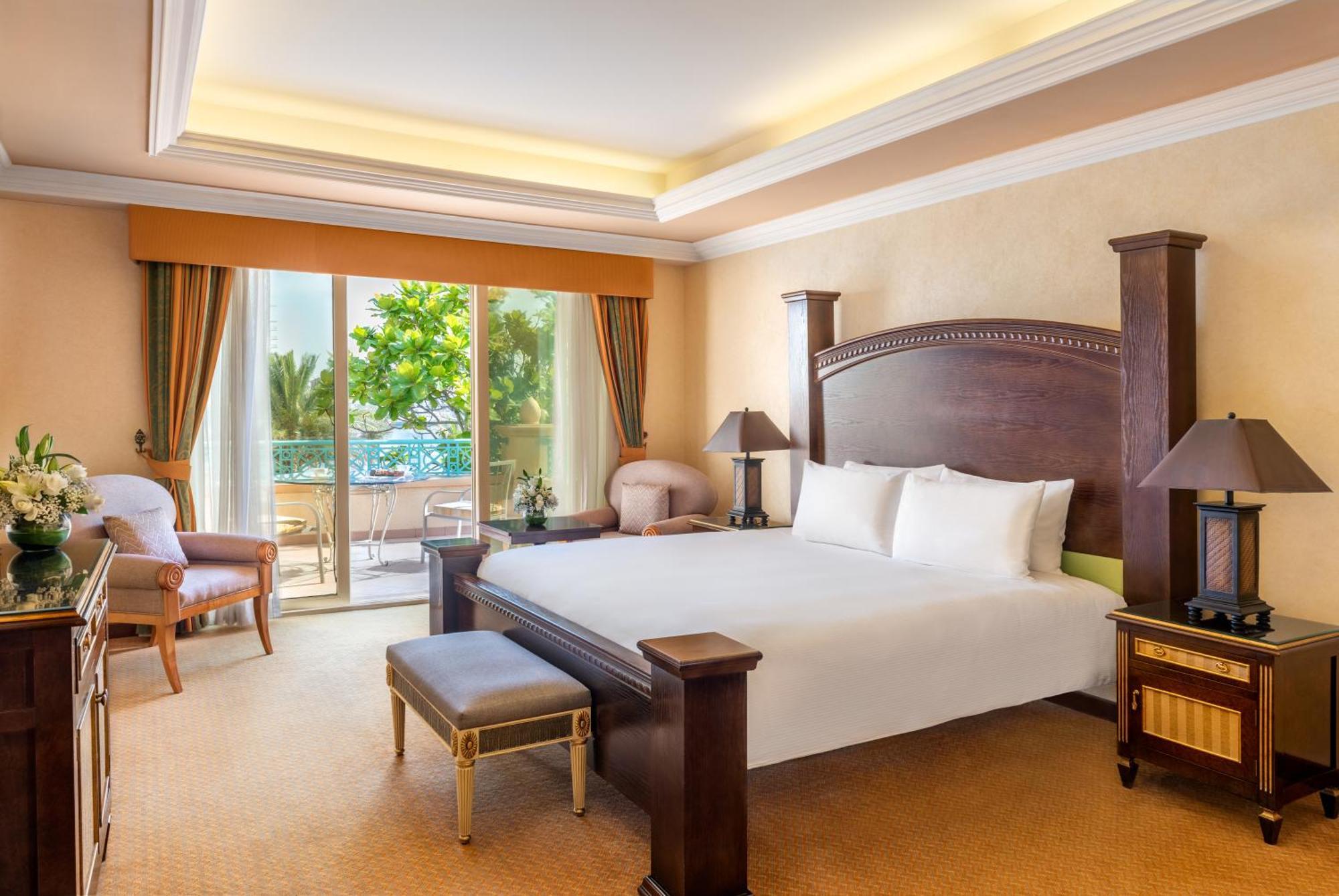 Al Raha Beach Resort & Spa Abu Dhabi Exterior photo The photo shows a well-appointed hotel bedroom. It features a large bed with white bedding, flanked by bedside tables with lamps. The room has light-colored walls and a warm-toned carpet. There is a comfortable seating area with a chair and a small t