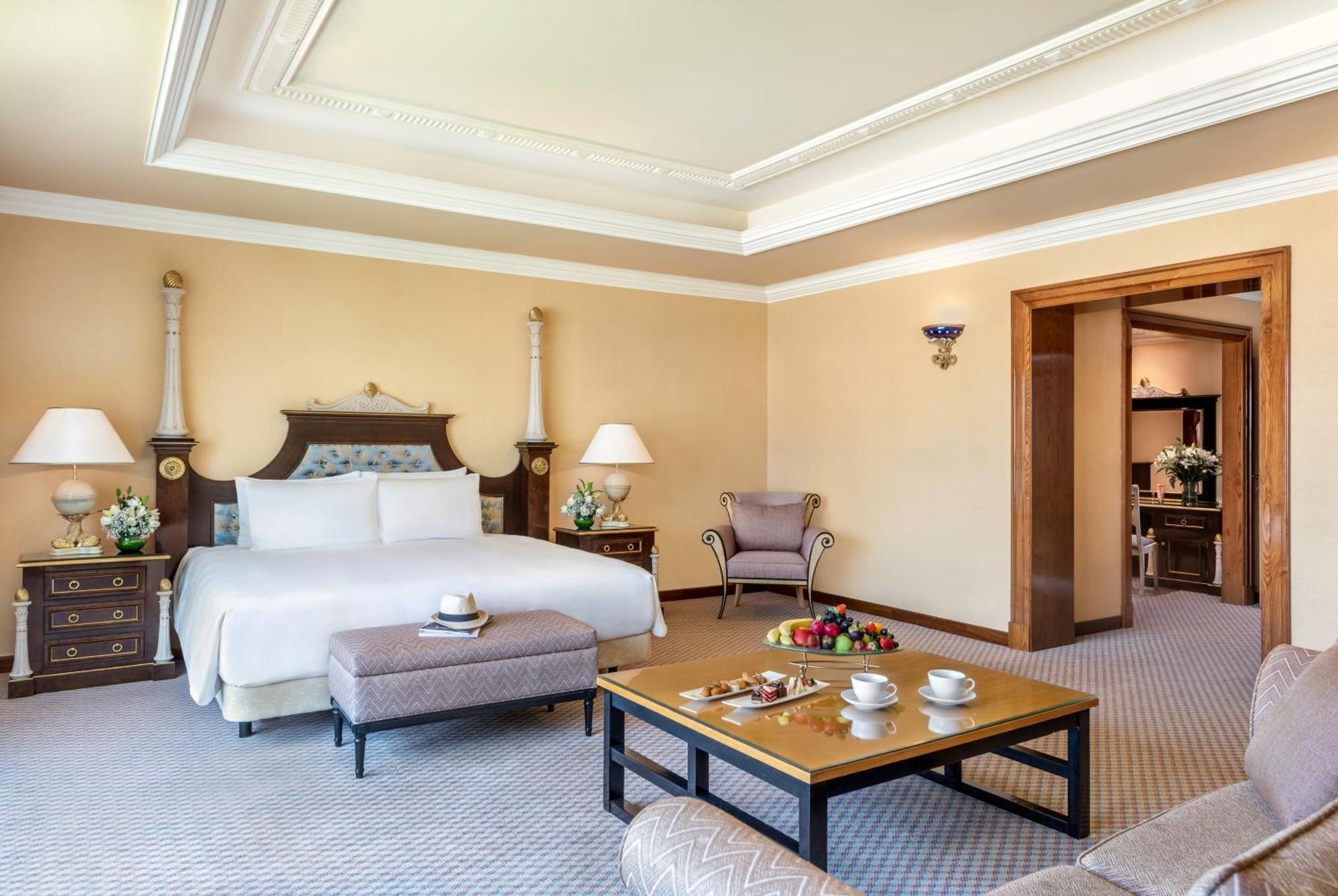 Al Raha Beach Resort & Spa Abu Dhabi Exterior photo The photo shows an elegant hotel room, featuring a large bed with white linens, flanked by stylish bedside tables and lamps. The room has a warm color palette, with light brown walls and a plush carpet. A comfortable armchair is positioned nearby, an